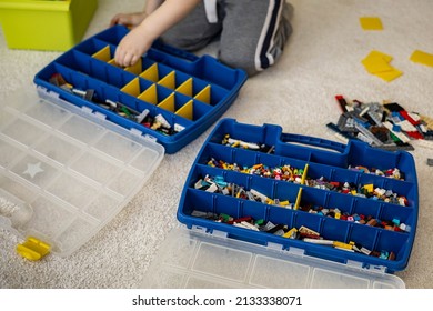 Khabarovsk, Russia, February 18, 2022. Boy Sorting Lego Colored Pieces Into Boxes With Small Cells. Constructor Toy Storage System, Home Cleanup. Male Kid Putting Blocks To Containers At Childish Room