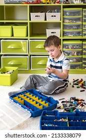 Khabarovsk, Russia, February 18, 2022. Cute Boy Sorting Lego Into Boxes With Cells. Children's Room With Constructor Details Vertical Storage System. Male Kid Neatly Folded Pieces Home Cleanup