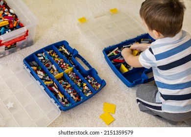 Khabarovsk, Russia, February 18, 2022. Boy Sorting Lego Colored Pieces Into Boxes With Small Cells. Constructor Toy Storage System, Home Cleanup. Male Kid Putting Blocks To Containers At Childish Room