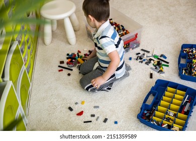 Khabarovsk, Russia, February 18, 2022. Boy Sorting Lego Colored Pieces Into Boxes With Small Cells. Constructor Toy Storage System, Home Cleanup. Male Kid Putting Blocks To Containers At Childish Room