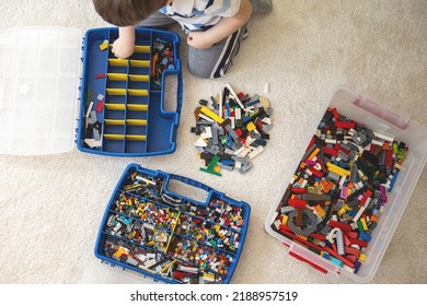 Khabarovsk, Russia, February 18, 2022. Boy Sorting Lego Colored Pieces Into Boxes With Small Cells. Constructor Toy Storage System, Home Cleanup. Male Kid Putting Blocks To Containers At Childish Room