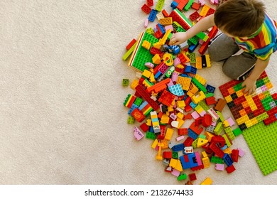 Khabarovsk, Russia, February 25, 2022. Top View Cute Baby Boy Playing Lego Duplo Multicolored Pieces On Beige Carpet. Male Kid Constructing Building Plastic Brick Toy Kindergarten Entertainment