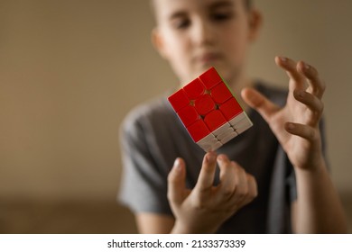 Khabarovsk, Russia, February 27, 2022. Closeup male teen hands hold multicolored flying Rubik's Cube 3x3. Logic intelligence creative algorithm challenge solving thinking solution with twisted block