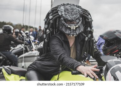 Khabarovsk, Russia - May 7, 2022: Female motorcyclist wearing a predator-style helmet rides a motorcycle. An exotic motorcycle helmet based on the science fiction franchise "Predator"