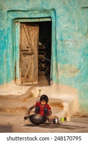 KHAJURAHO, INDIA - APRIL 15, 2011: Unidentified Girl Cleaning Kitchen Cooking Pan In Village Street. Child Labour Is Still Comon In India