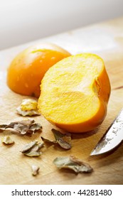 Khaki Fruit On Wood Sliced In Parts With Knife