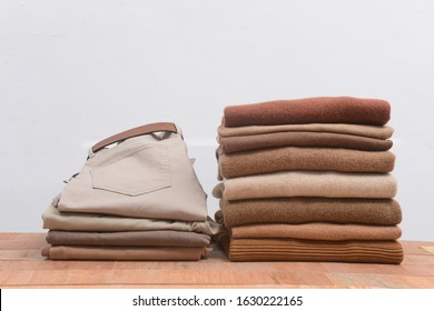 Khaki Pants With Different Knitting Patterns Folded In Stack On Brown Wooden ,gray Wall Background


