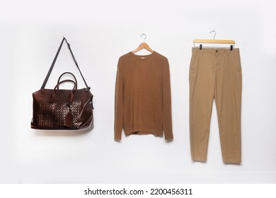 Khaki Pants And Sweaters With Shirt, And Handbag On Hanging On The White Background