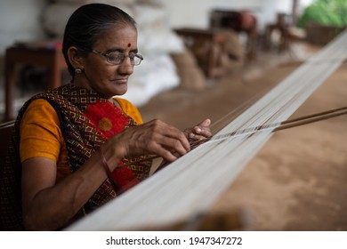 Khargone, Madhya Pradesh, India- July 14 2016:  woman doing warping and straightening process on wool thread,  with the desi comb called  Kilori 