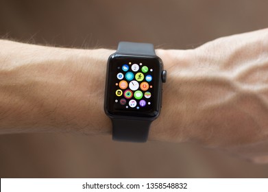 Kharkiv, Ukraine - April 03, 2019: Smart Apple Watch Series 3 sports version silicone gray strap on man hand. The display shows main menu of the gadget. Multiple Apps View. Concept mobile modern