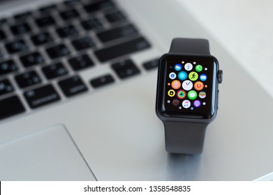 Kharkiv, Ukraine - April 03, 2019: Smart Apple Watch Series 3 sports version silicone gray strap are on the laptop. The display shows main menu of the gadget. Multiple Apps View. Concept mobile modern