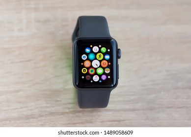 Kharkiv, Ukraine - August 27, 2019: Smart Apple Watch Series 3 sports version silicone gray strap on the wooden table. Display shows main menu gadget. Multiple Apps View. Close-up front view