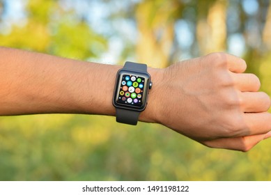 Kharkiv, Ukraine - August 29, 2019: Smart Apple Watch Series 3 sports version silicone gray strap on man hand outdoor in bright summer. The display shows main menu of the gadget. Multiple Apps View.