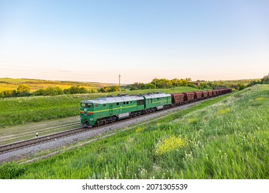 Kharkiv, Ukraine - Autumn 2021: An old green diesel locomotive pulls for export a long train of their wagons laden with grain. Railway transportation of grain harvest. Ukrainian railway