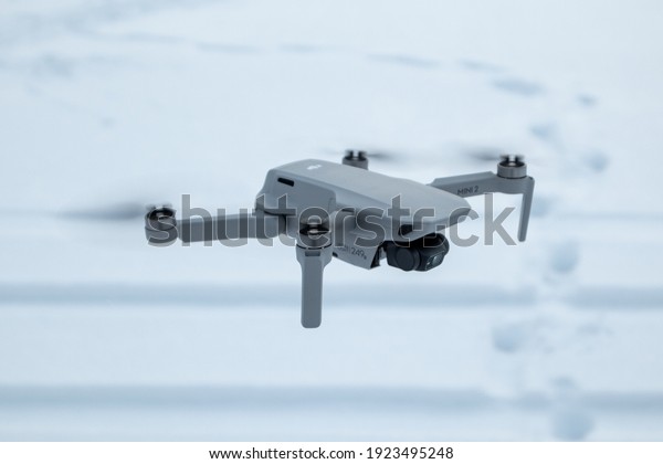 Kharkiv, Ukraine - February 21, 2021: Dji Mavic\
Mini 2 drone flying close-up. New quadcopter gadget on white snow\
winter background. Side\
view