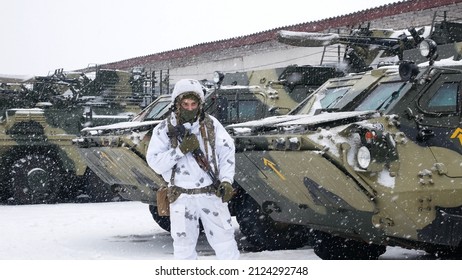 Kharkiv, Ukraine - January, 31, 2022: A Ukrainian soldier in a white camouflage uniform stands near armored personnel carriers. The Ukrainian army is preparing to defend its territory from the Russian
