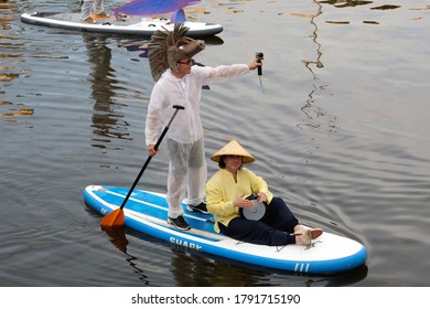 KHARKIV, UKRAINE JULY 17, 2020: Two Guys Ride SUP Boards On The River. A Guy Dressed In A White Suit And A Horse Mask. The Guy Stands On SUP Boards And Shoots With A Go Pro Camera. Party On The Water