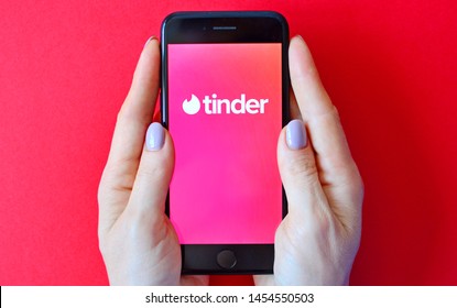 KHARKIV, UKRAINE - JULY 18, 2019: Illustrative editorial of Tinder logo on smartphone screen in female hands.
