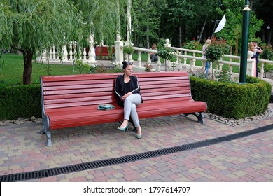 KHARKIV, UKRAINE JULY 22, 2020: A Young Woman With A Serious Expression Sits On A Bench In The Park. A Beautiful Woman In Trousers And A Jacket Sits Alone And Waits. Woman 30 Years Old Brunette