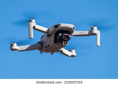 Kharkiv, Ukraine - March 6, 2021: Dji Mavic Mini 2 drone close-up with camera lens filter on, flying in sunny day. New quadcopter device hovering on blue sky background