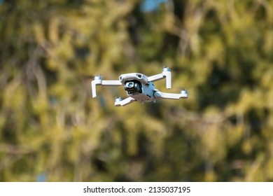 Kharkiv, Ukraine - March 6, 2021: Dji Mavic Mini 2 drone, flying in sunny day forest. New quadcopter device hovering with blurry green background
