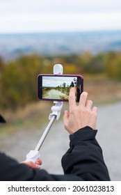 Kharkiv, Ukraine - October 20, 2021: Man Hands Takes A Vlog On Iphone With A Monopod To Stabilize Video. Montage While Traveling In Nature. Helpful Gadgets To Go Sightseeing. 4k Video On Smartphone