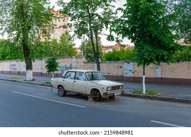 Kharkiv, Ukraine - Spring 2022: A car of refugees parked on the street near the railway station is plundered by looters. Theft of wheels from a car. War in Ukraine.