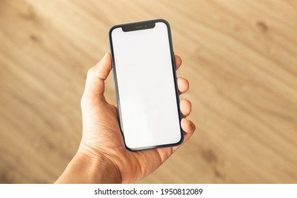 Kharkov, Ukraine - April 3, 2021: Man Hold Apple IPhone 12, Mockup With Blank White Screen