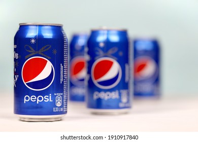KHARKOV, UKRAINE - DECEMBER 8, 2020: Aluminium cans of Pepsi soft drink on white wooden table. Pepsi is carbonated soft drink produced by PepsiCo. Pepsi was created and developed in 1893