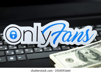 KHARKOV, UKRAINE - FEBRUARY 14, 2021: Onlyfans paper logo and dollar bills on black laptop keyboard. OnlyFans is content subscription service based in London, United Kingdom