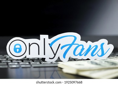 KHARKOV, UKRAINE - FEBRUARY 14, 2021: Onlyfans paper logo and dollar bills on black laptop keyboard. OnlyFans is content subscription service based in London, United Kingdom