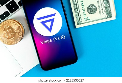 Kharkov, Ukraine - January 31, 2022: Velas VLX coin symbol. Trade with cryptocurrency, digital and virtual money, banking with mobile phone concept. Business workspace, table with laptop top view