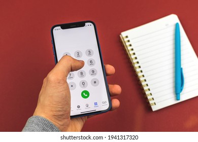 Kharkov, Ukraine - March 10, 2021: Man Holds Smartphone With Phone Call Screen, Person Writes Phone Number To Make Call