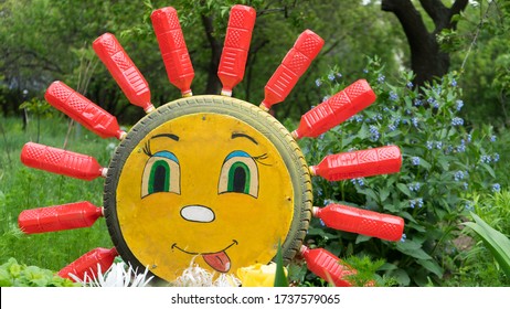 Kharkov, Ukraine May 20, 2020
Reused or recycling red plastic bottles and car tire sun craft in the garden. Bright colorful yellow sun made of plastic reusing bottles and tire in sunny garfen.Save env