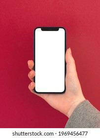 Kharkov, Ukraine - May 5, 2021: Hand Hold IPhone 12 With White Screen On Colorful Red Background, Mockup Photo