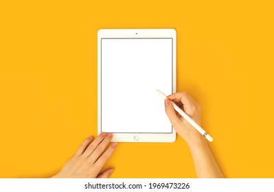 Kharkov, Ukraine - May 5, 2021: Mockup Of Apple IPad And Stylus Pen Pencil In Woman's Hand, Yellow Bright Background And Top View 