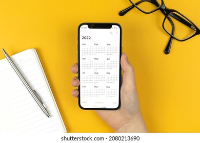 Kharkov, Ukraine - November 17, 2021: Calendar for 2022 on Apple iPhone screen. Calendar app. Business workspace with notepad and pen, top view 