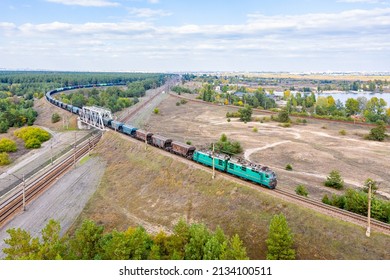 Kharkov, Ukraine - summer 2021: A powerful green locomotive pulls a long train loaded with grain and corn to the seaport. Aerial view. Ukrainian railways.