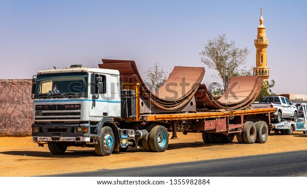 Khartoum, Sudan, February 6, 2019: Heavy-duty\
truck with large iron components on the loading area during\
transport through the\
desert