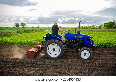 Kherson oblast, Ukraine - May 29, 2021: Farmer on a tractor cleans the field after harvest. Running a small agribusiness. Farm work. Farming. Loosening, land cultivation. Mechanization in agriculture.