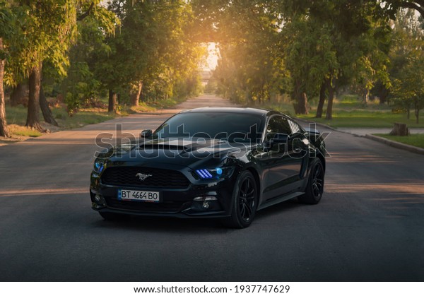 Kherson, Ukraine - July\
2018. American muscle car Ford Mustang in a black color with a blue\
headlights.