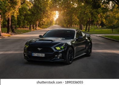 Kherson, Ukraine - July 2018. Powerful American Muscle Car Ford Mustang In A Black Color With Green Headights.