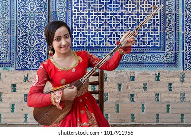 KHIVA, UZBEKISTAN - MAY 24, 2017: Uzbek Woman In National Costumes Play Local Musical Instrument Of Dutar, In Khiva, Uzbekistan.