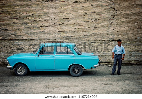 Khiva\
/ Uzbekistan - MAY 5 2010: taxi driver next to his classic soviet\
car in the historical walled city of the silk\
road