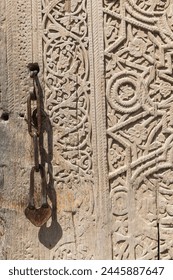 Khiva, Xorazm Region, Uzbekistan, Central Asia. Rusted chain handle on an old carved wooden door.