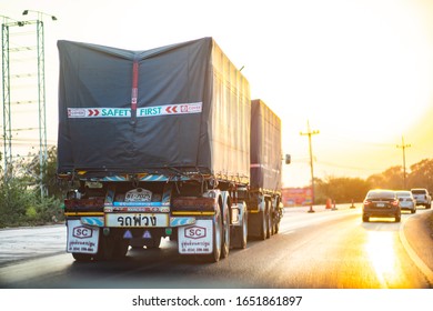 Khon Kaen, Thailand, Feb 20, 2020 - Big black trailer truck for logistic driving on road to North Eastern Thailand region with sun warm light in the evening