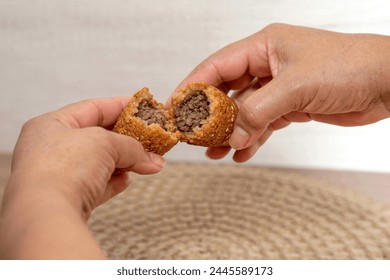 Kibbe traditional Arabic food, kibbe is a fried food filled with minced meat. It is characterized by its ovoid shape ending in two pointed ends. Hands showing a kibbe cut in half