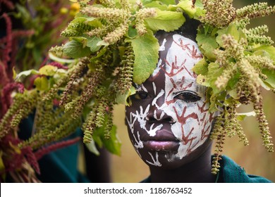 KIBISH, ETHIOPIA - AUGUST 22, 2018: unidentified boy from Surmi tribe, with painted face and natural decorations of leave. Surmi are also called Suri or Surma