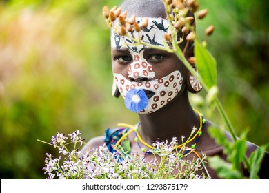 KIBISH, ETHIOPIA - AUGUST 22, 2018: unidentified woman from Surmi tribe, with  painted face and natural decorations of leave and flowers in a wreath. Surmi are also called Suri or Surma