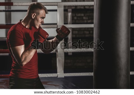 
Kickboxer exercises blows on the pear in the gym. Mixed figher trains in the oldschool gym.
